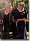 A sighted person assists an elderly blind man with mobility training